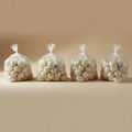 Four clear plastic bags filled with frozen dumplings on a beige background