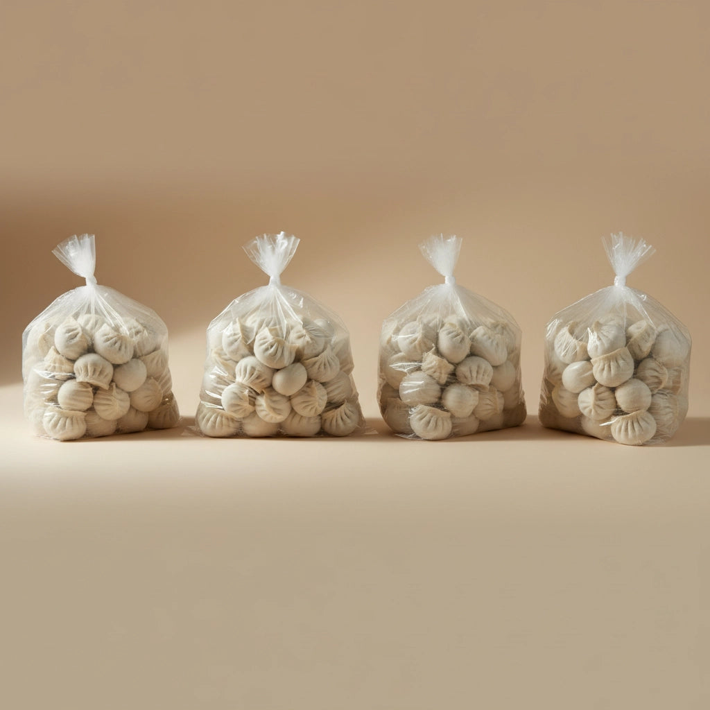 Four clear plastic bags filled with frozen dumplings on a beige background